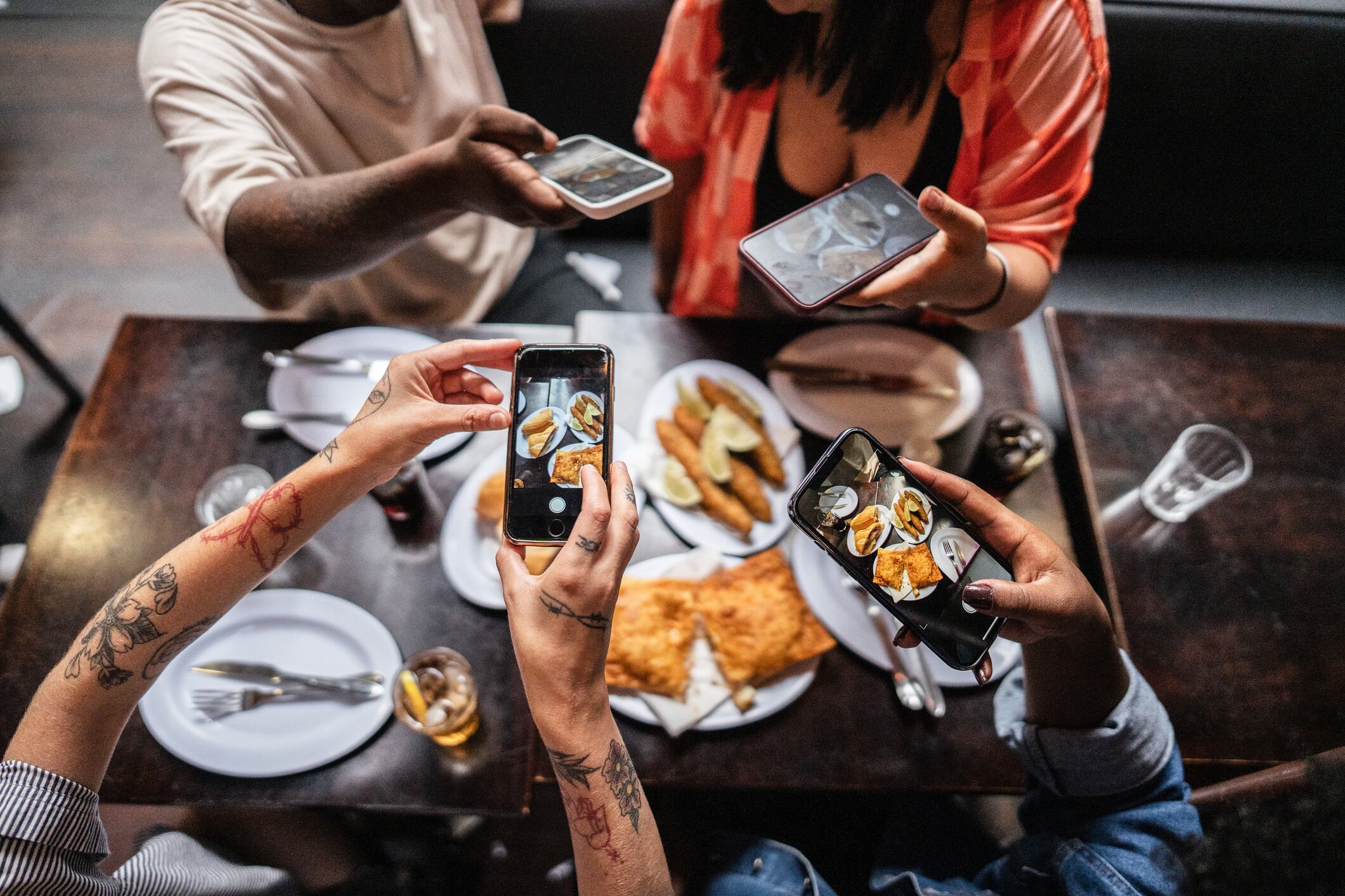 Friends taking photos of food at restaurant