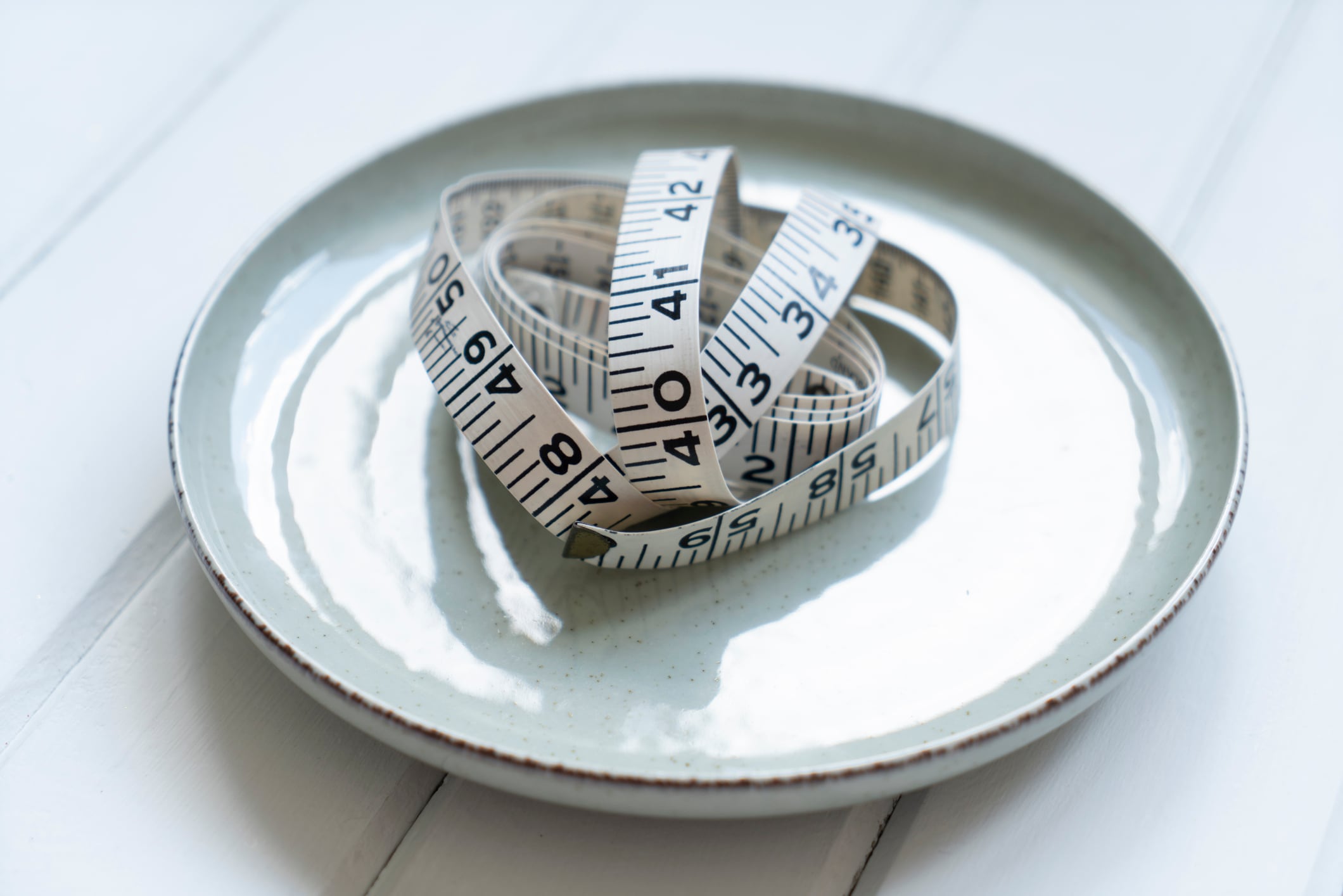 Plate and measuring tape on wooden background, flat lay. Diet concept