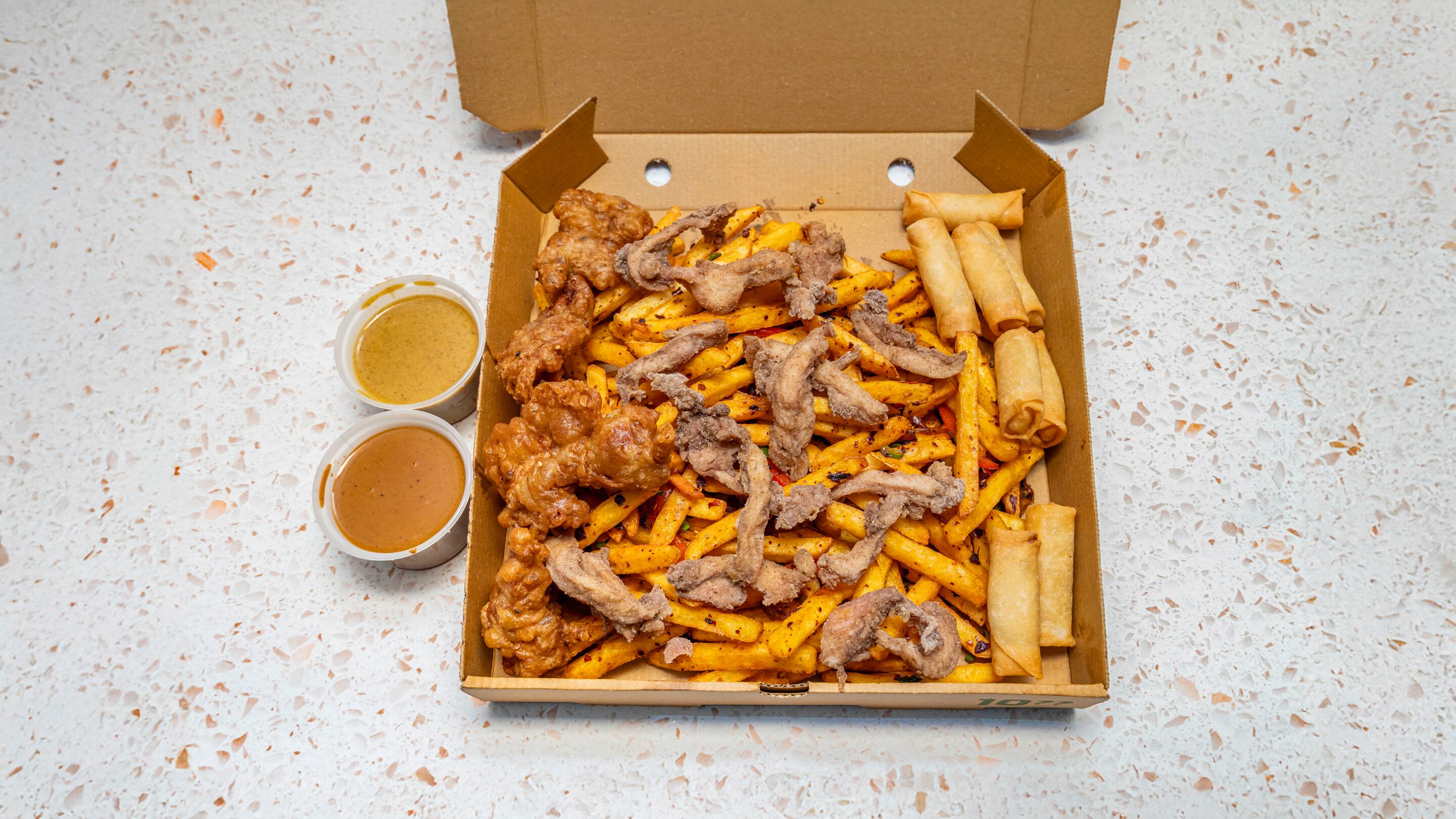 A pizza box full of chips, fried chicken and spring rolls