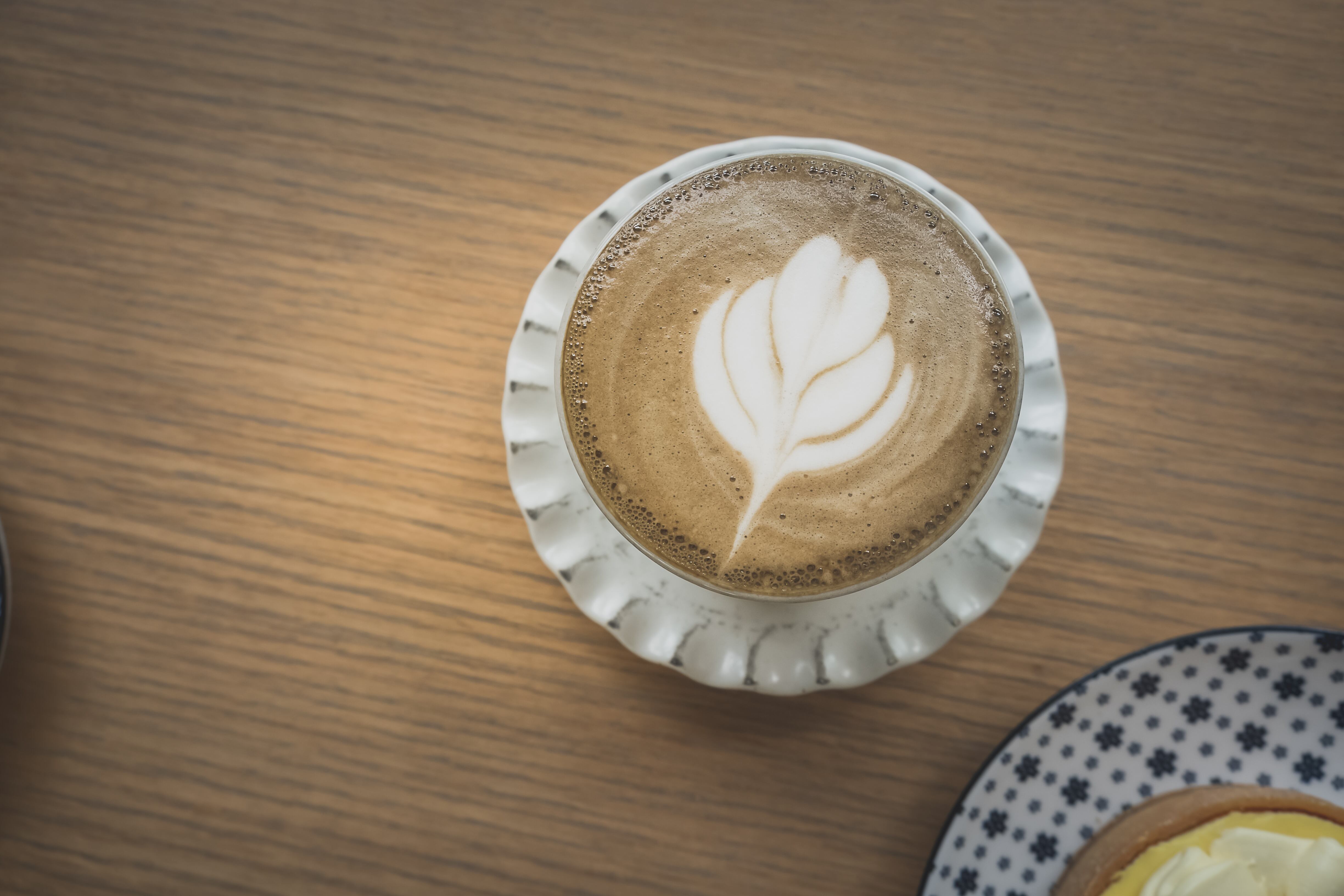top view cup of hot hojicha green tea latte with beautiful latte art on wood table