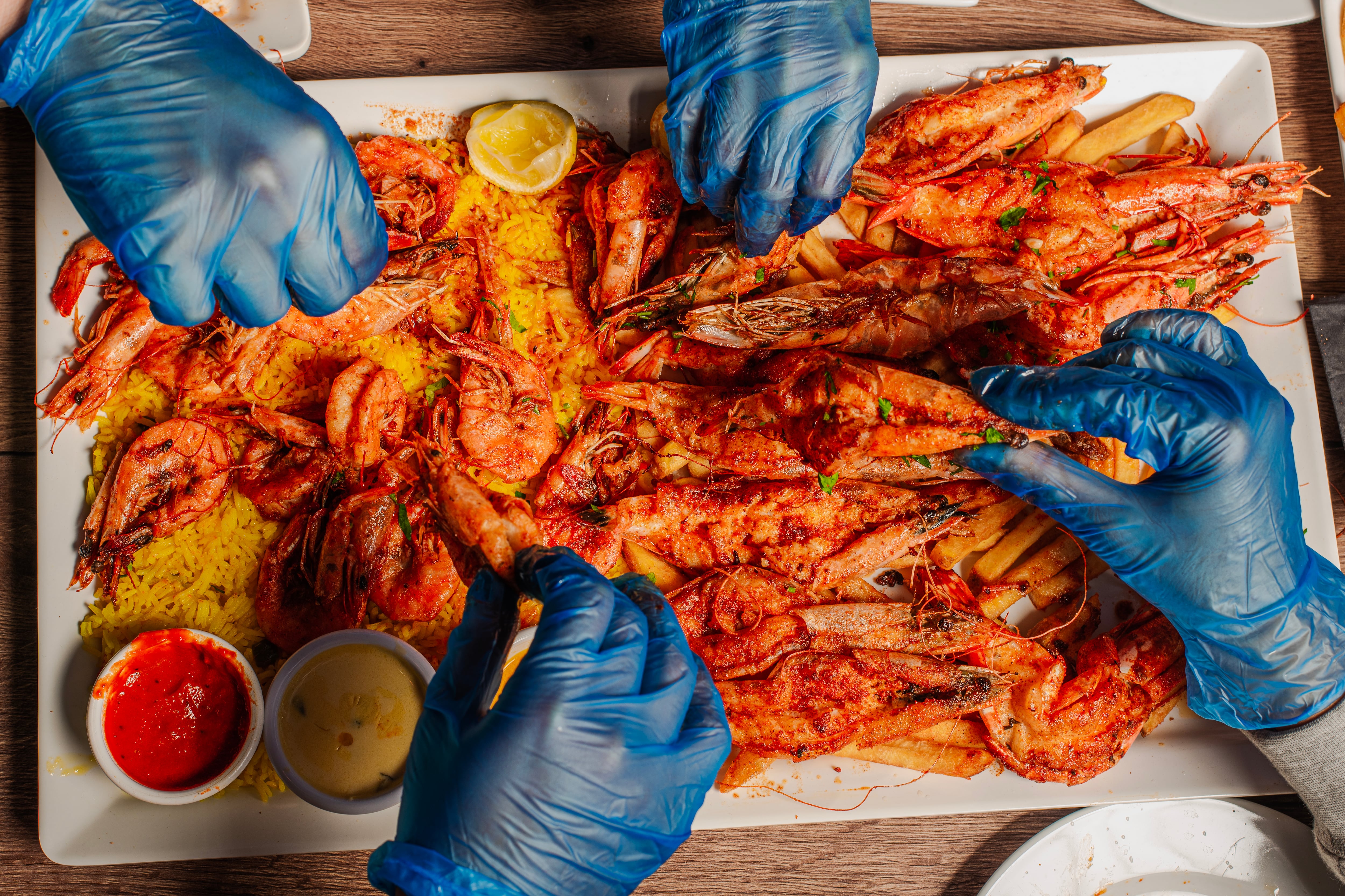 Hands picking seafood from a plate