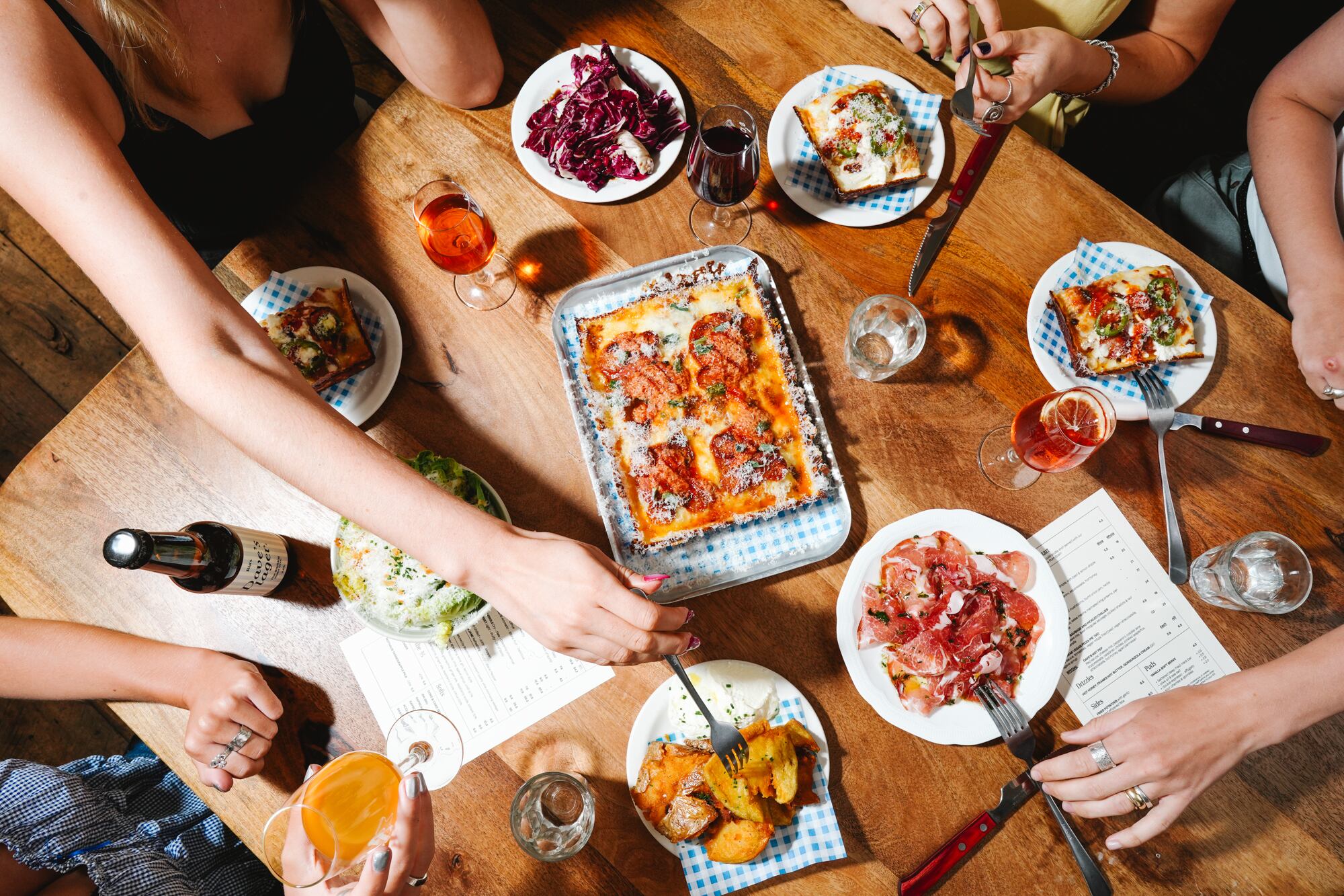 Detroit-style pizzas and sides on a table at Ria's