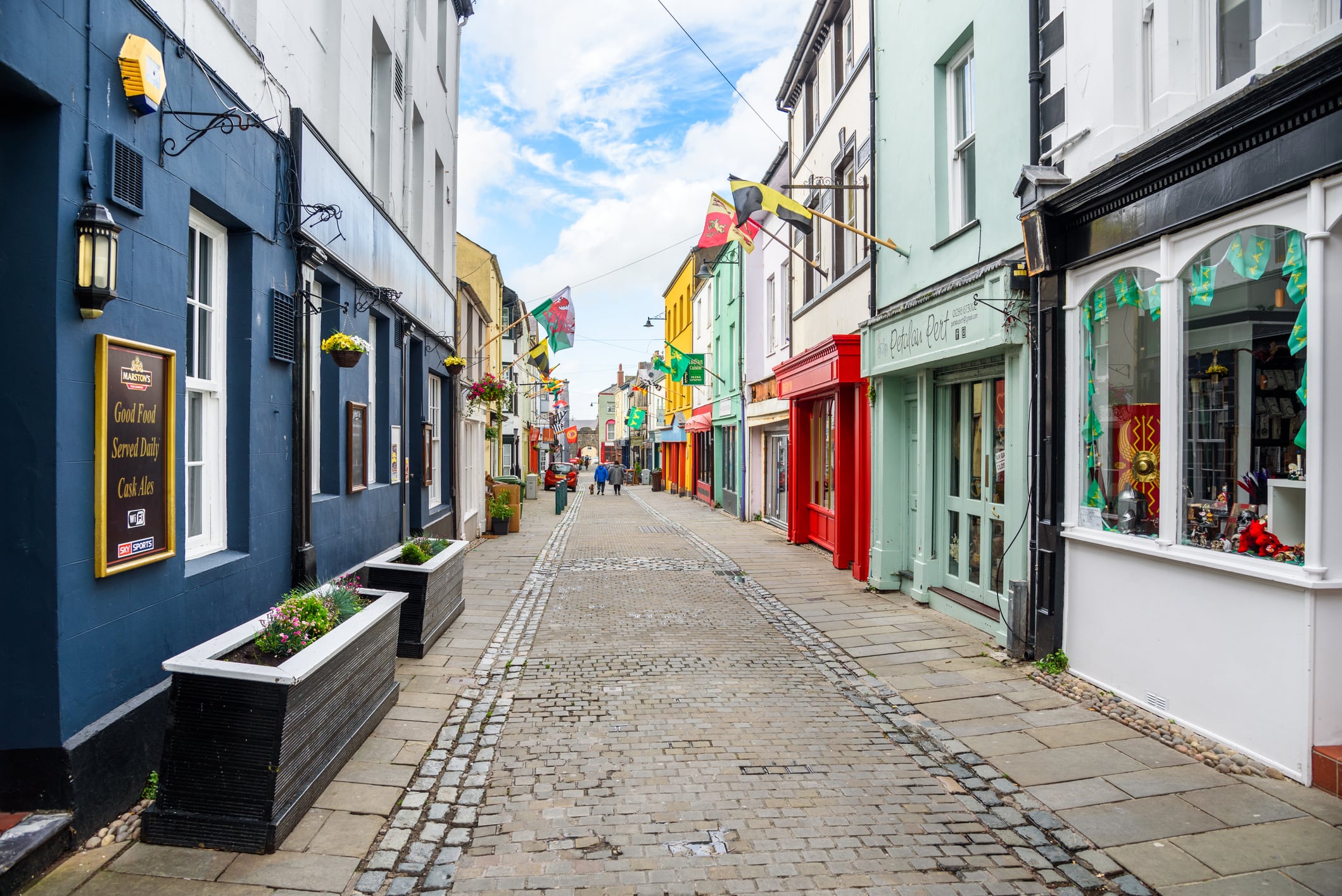 Caernarfon, Wales, UK - July 10, 2023: people walking along Palace street in the old town. Caernarfon is a bustling market town with a busy port, as well as magnificent views over the Menai Strait, the channel that separates Anglesey from mainland Wales.