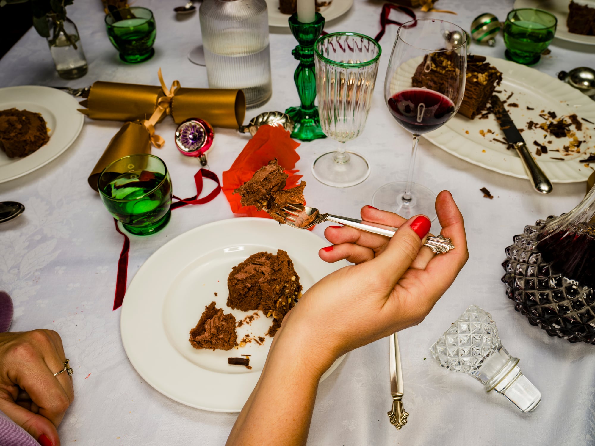 Close Up Over The Shoulder View Hands Of Woman Eating Chocolate Yule Log Christmas Dessert At Dining Table