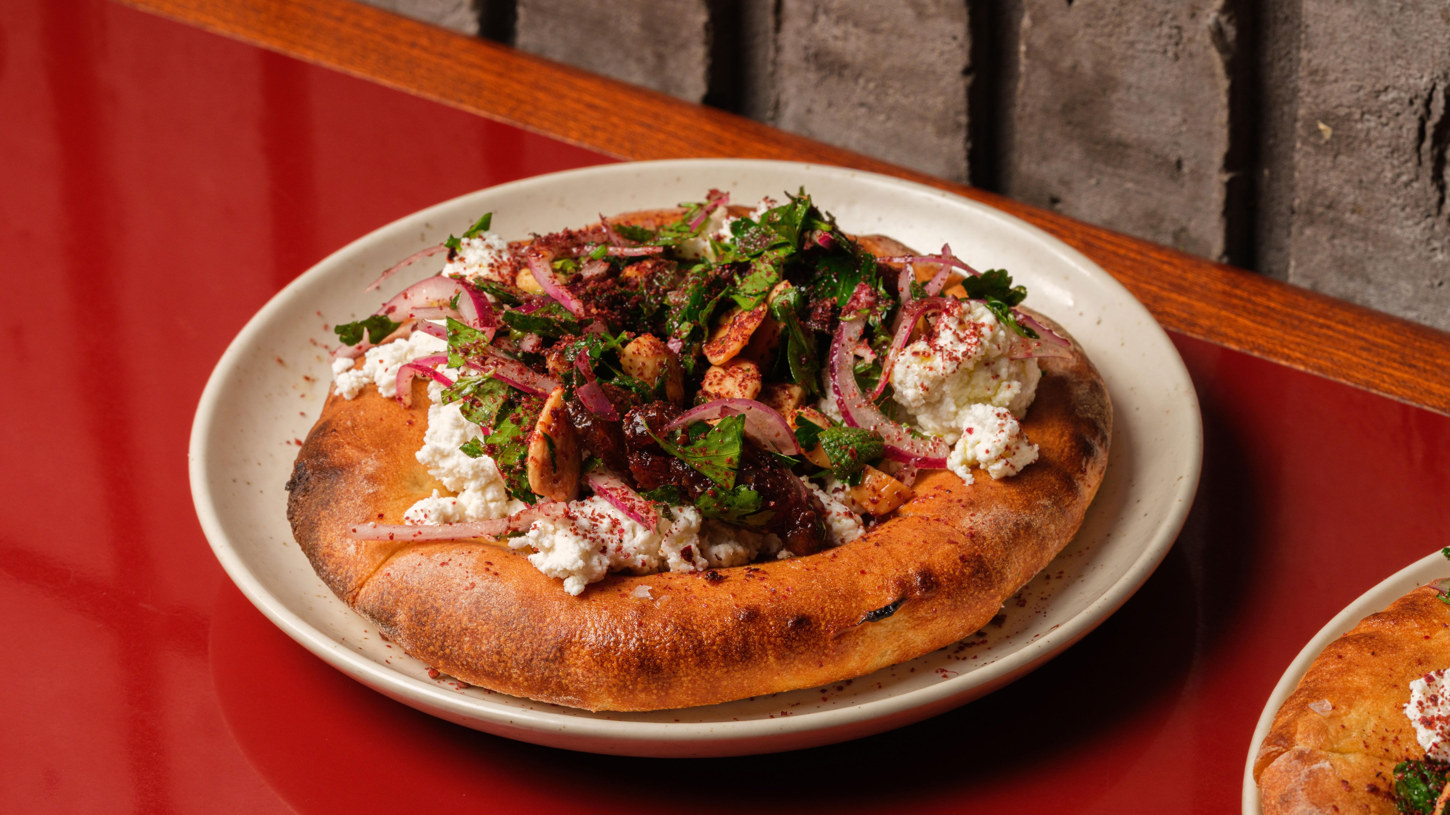 Pizza fritta topped with fresh ricotta, dates, sumac, and mint