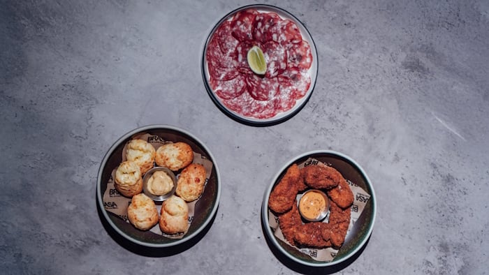 Brazilian Cheese Bread (Pão-de-Queijo) and Caramelised Onion Butter; Brasa Charcuterie - Lomo, Fennel Salami, Spianata Romana and House Pickles; Annatto Crispy Chicken Fillets and Smoked Chilli Mayo