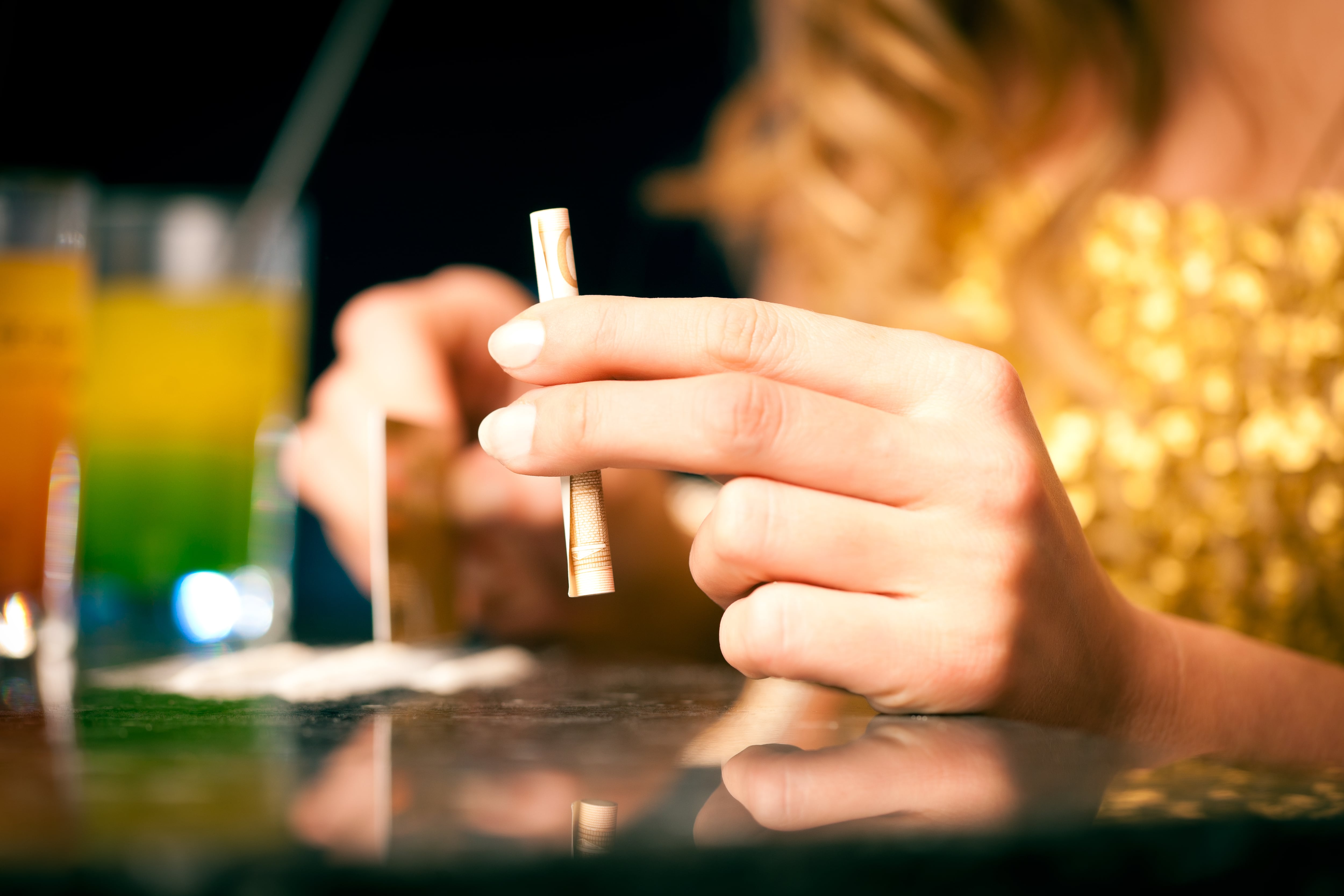 Young woman snorting cocaine and is cutting the cocaine with a credit card and sniffing with a bill, close-up