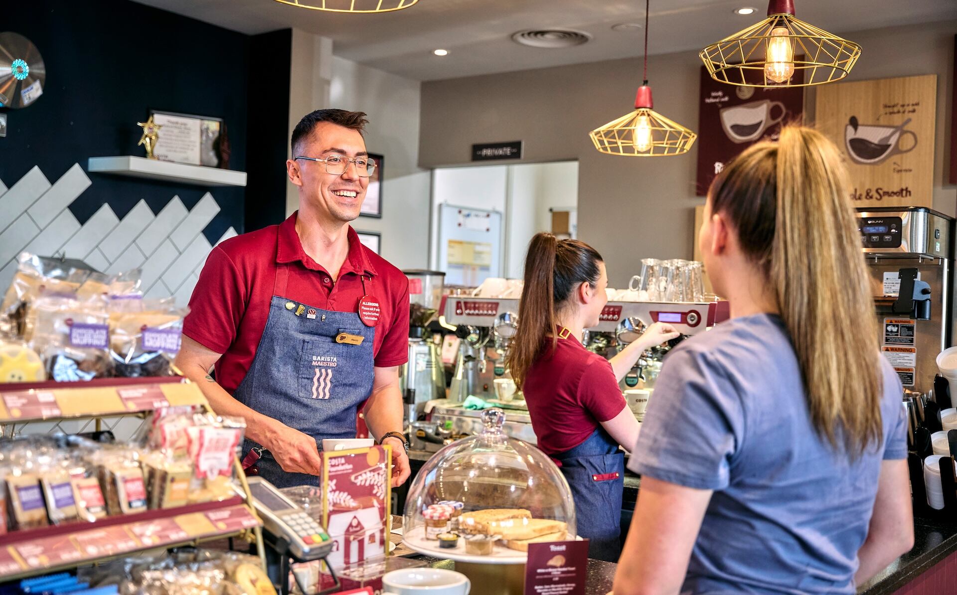 A man serving a customer at Costa Coffee