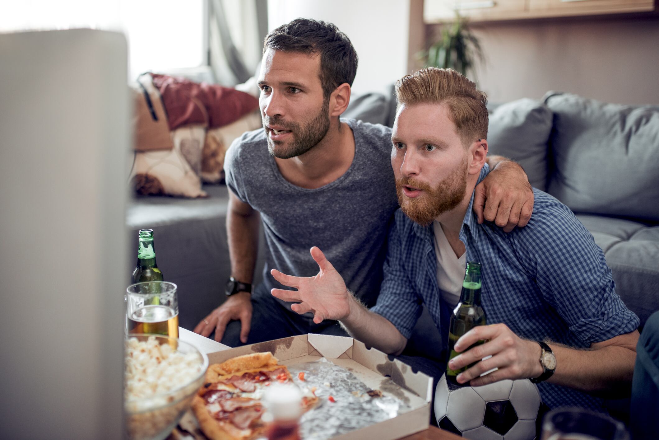 Friendship,sport,people and entertainment concept-happy football fans watching soccer on tv at home.