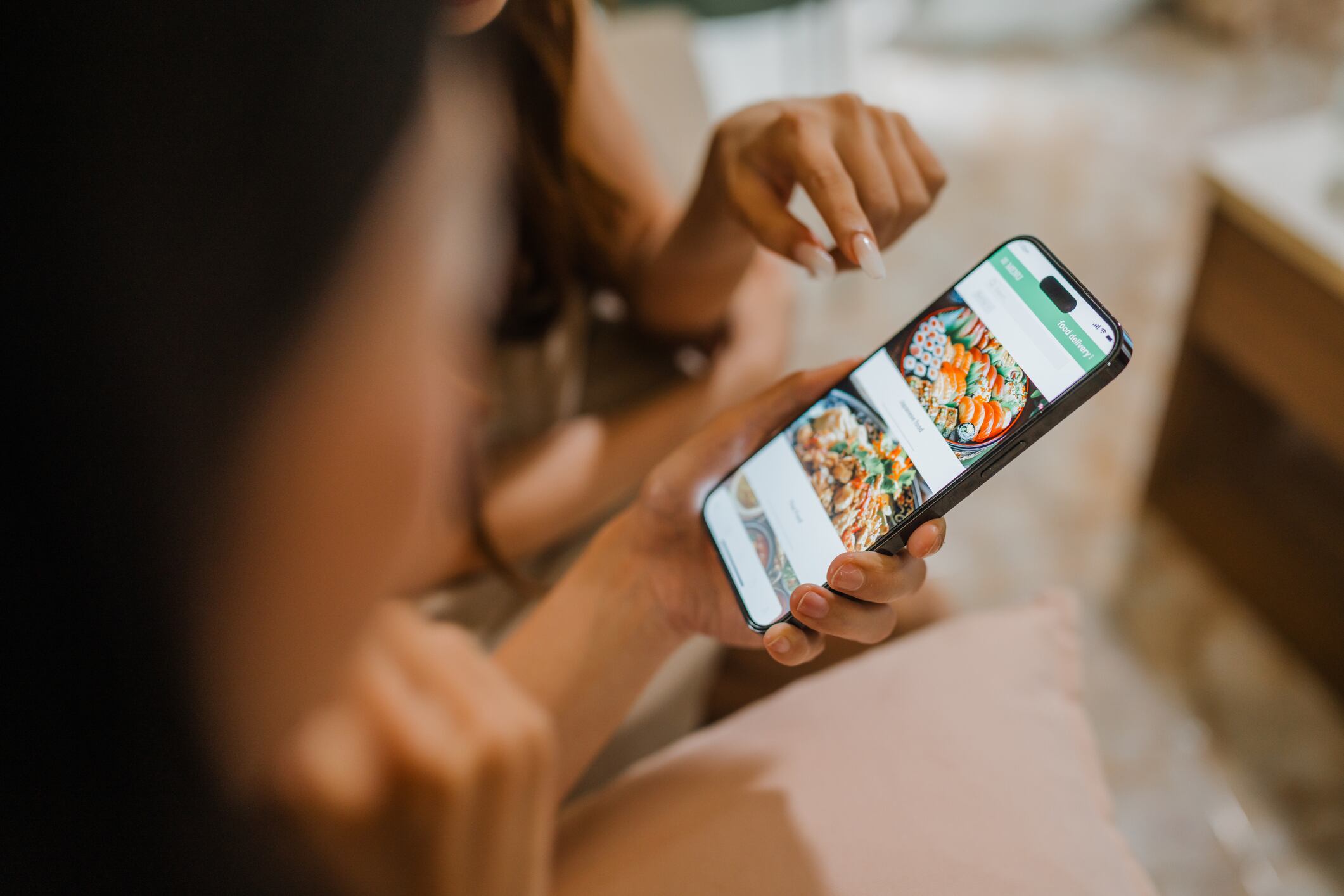Young Asian women using food ordering app while relaxing indoors