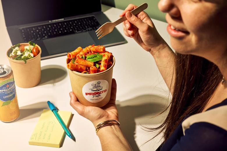 Woman eating pasta at her desk