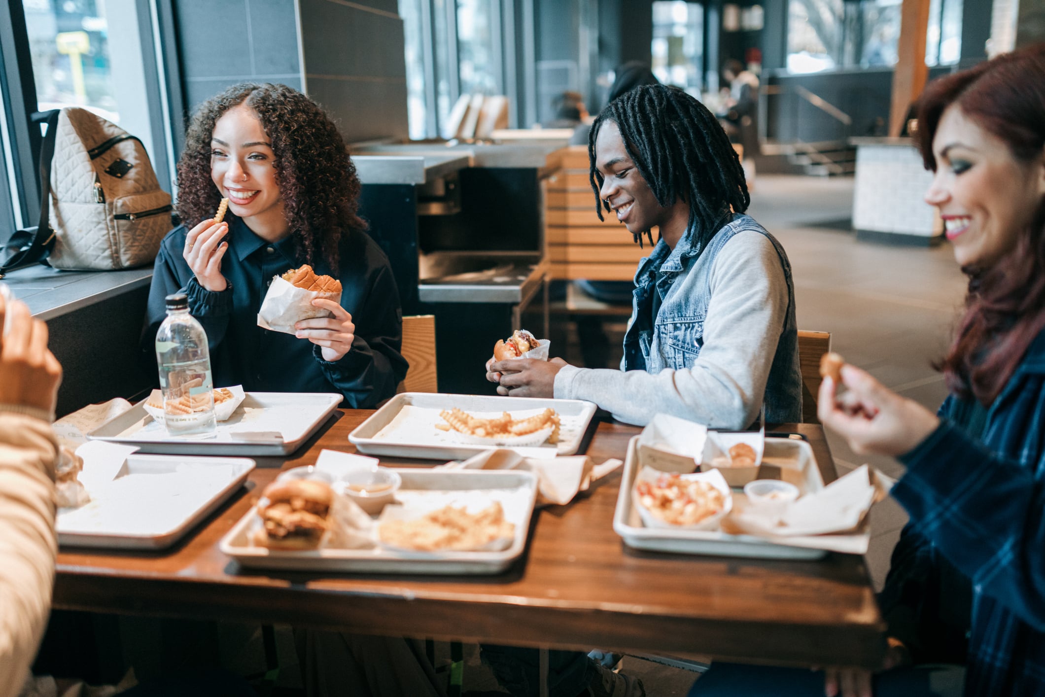 A group of African American young adults dine out at a restaurant, enjoying tasty food and good company. Shot in Seattle Washington.