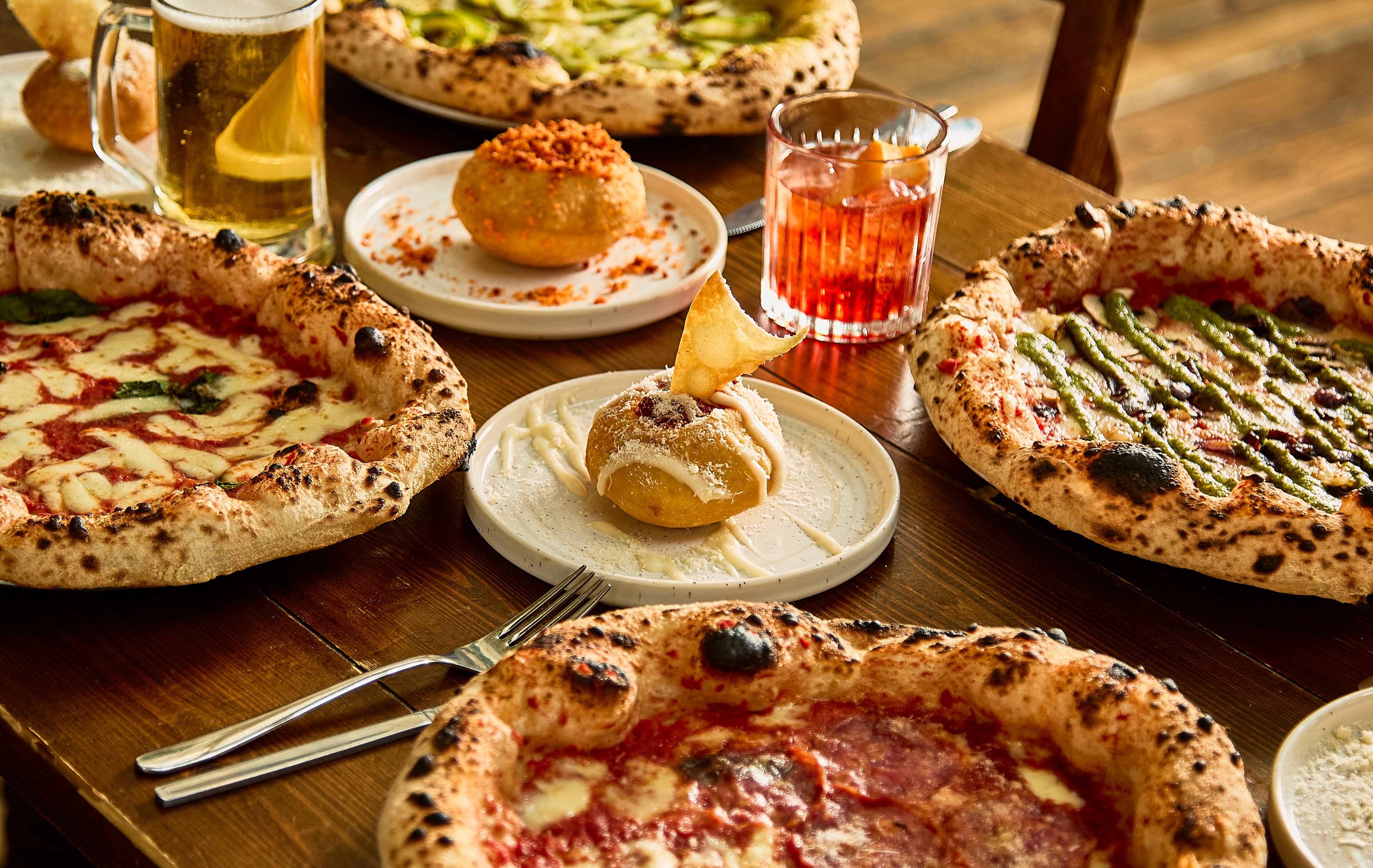 A table laden with pizzas and 'bombas' at Crust Bros in Covent Garden