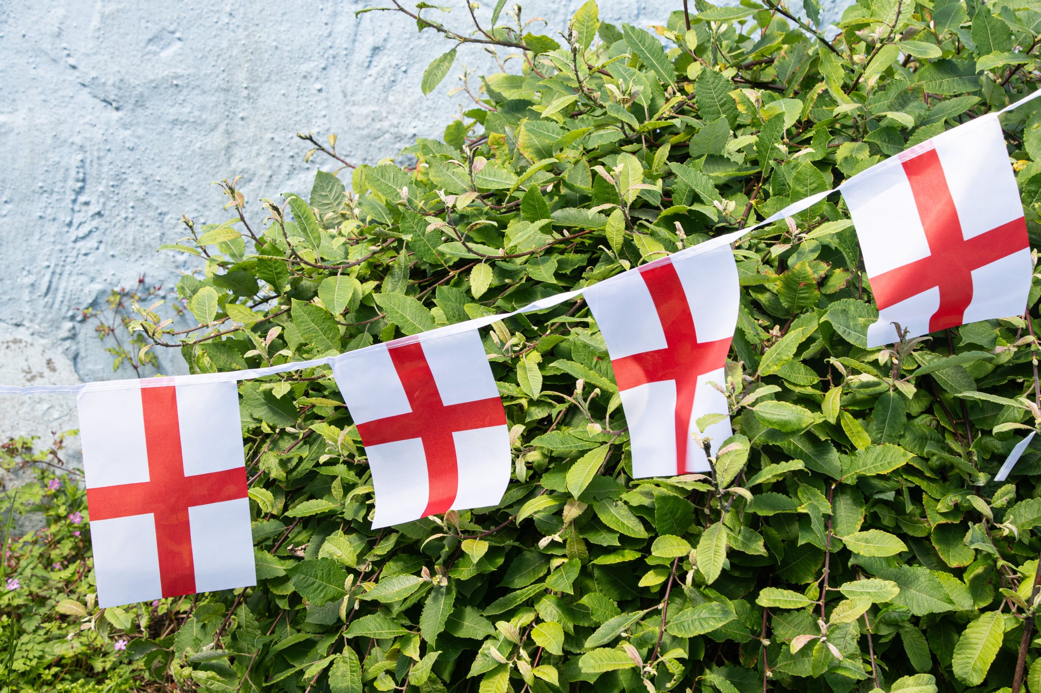 Traditional England flag bunting displayed outdoors during a major football tournament celebration. Red and white St George’s Cross flags hanging in a festive arrangement, symbolizing national pride, fan support, and excitement during the World Cup. Ideal for themes of sport, football, patriotism, celebrations, tournaments, community events, and English culture.