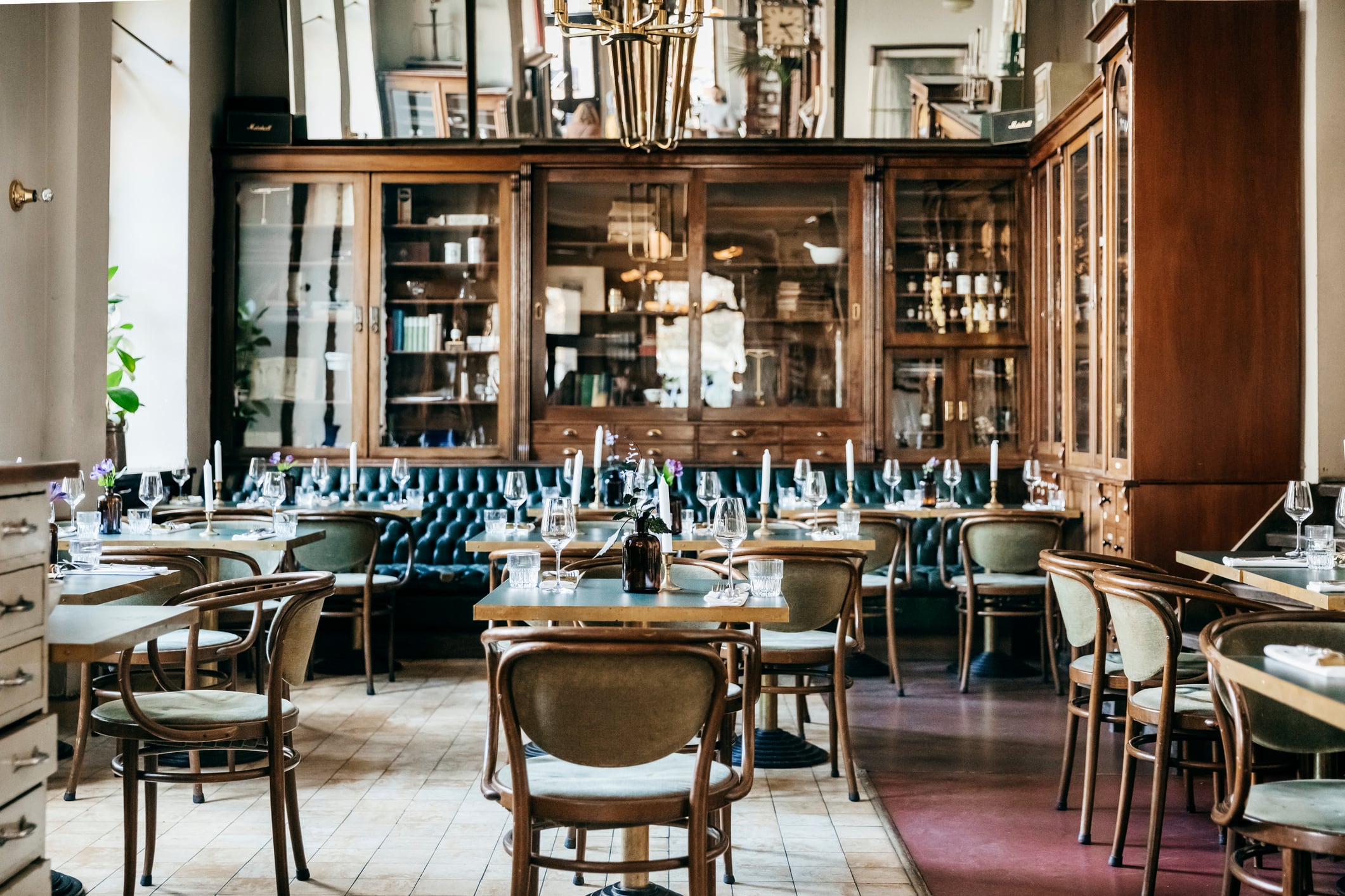 An empty luxurious restaurant with large wooden cabinets and leather seating.